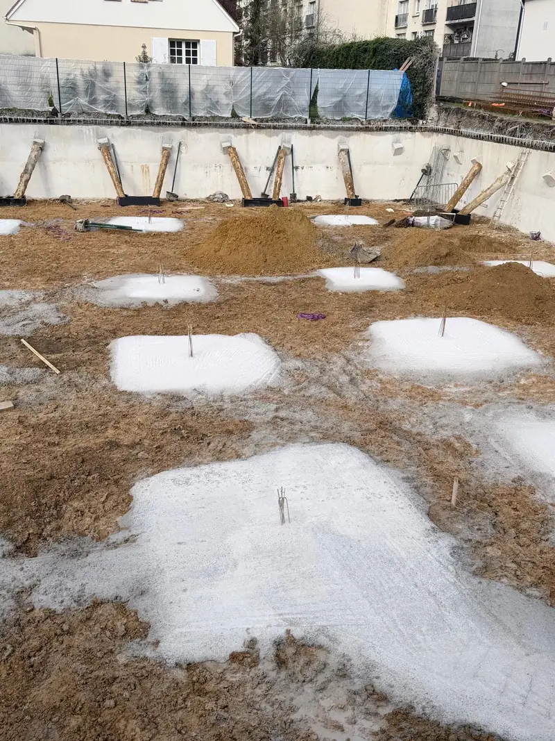 Fond de fouille avec semelles en béton coulées, attentes en acier dressées.