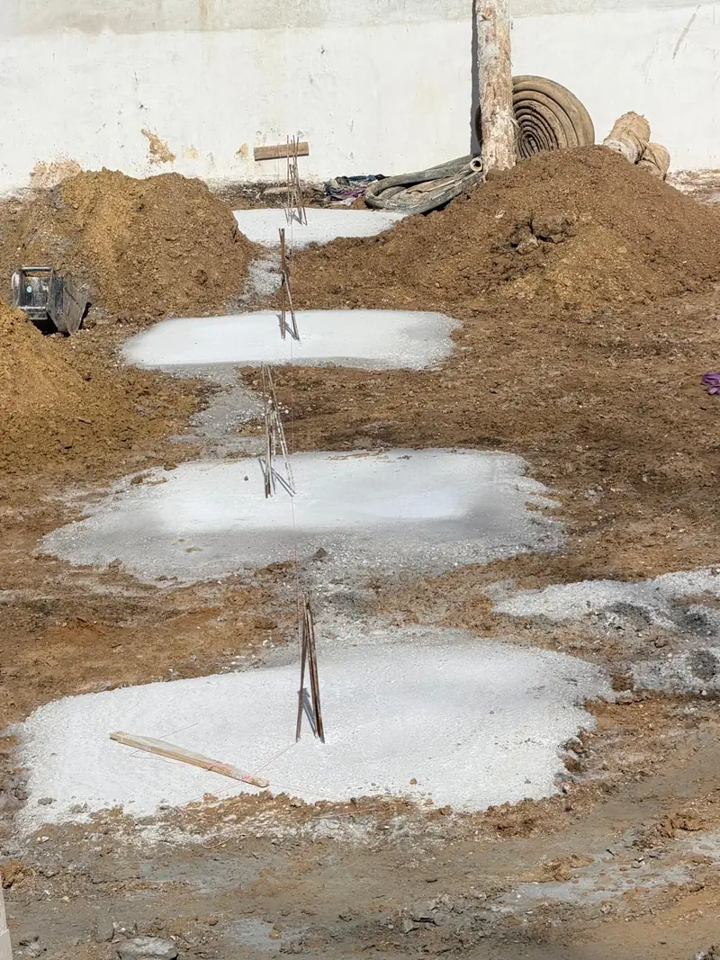 Rangée de semelles de béton coulées avec attentes en acier.