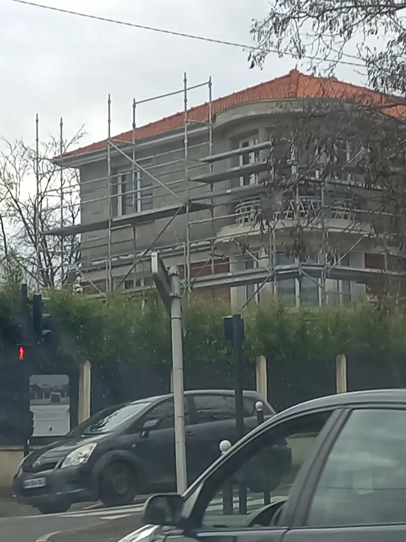 La villa sous échafaudage pendant les travaux de surélévation, toiture en tuiles rouges.